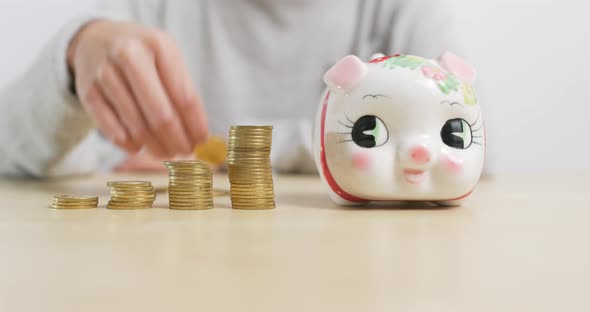 Woman putting coins into piggy bank