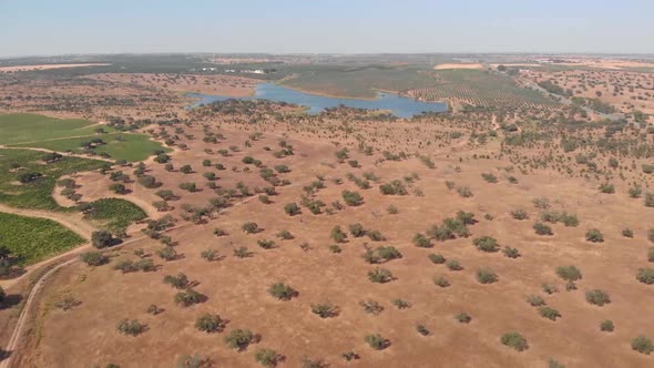 Aerial forward shot of dry desert and lake in background during hot summertime in Portugal