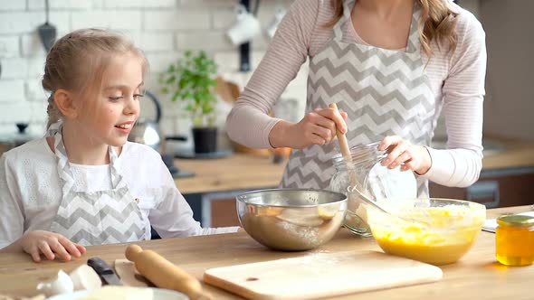 Mother Pouring Flour in To the Bowl, While Little Daughter Looking and Learning