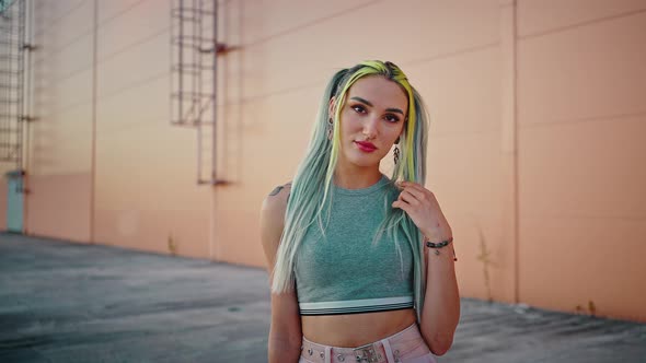 Close Up Portrait of Young Lady with Colorful Hairstyle and Piercing on Face Looking at Camera