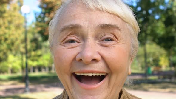 Positive Old Woman Laughing Outdoors Enjoying Good News, Surprise Happiness