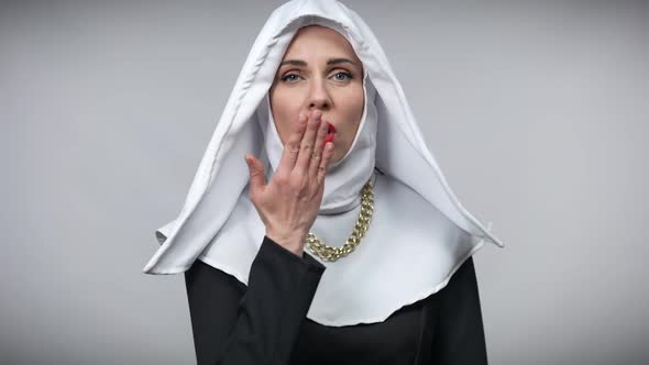 Beautiful Smiling Woman in Nun Costume Sending Air Kisses Looking at Camera Posing at Grey