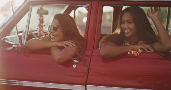 Two girl friends having fun in their vintage car alt