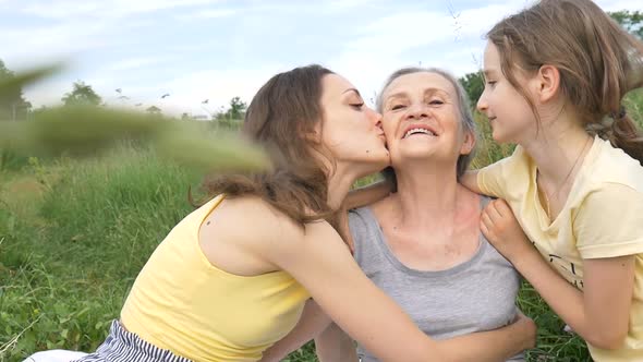 Cute Child Girl with Her Young Mother and Senior Grandmother are Having Picnic During Summer Outdoor