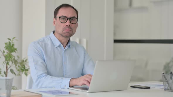 Middle Aged Man with Laptop Shaking Head As No Sign