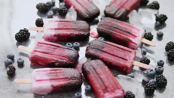 Homemade Blackberry and Cream Ice-creams or Popsicles with Frozen Berries on Black Slate Tray