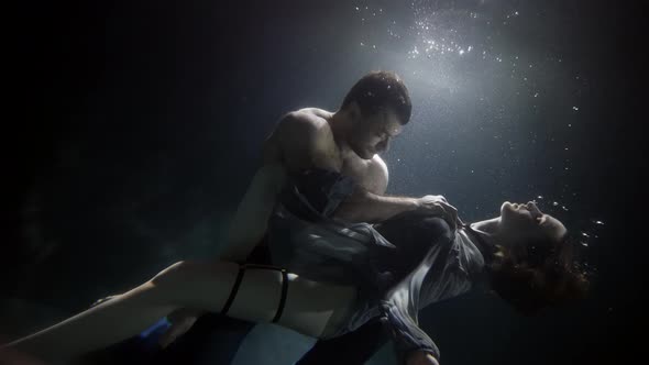 A Man Touches and Passionately Holds His Girlfriend Underwater Lovers Deep Inside on a Dark