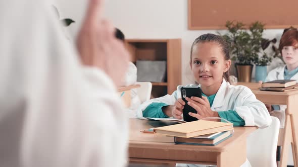 Adorable Little Girl Using Mobile Phone in Classroom