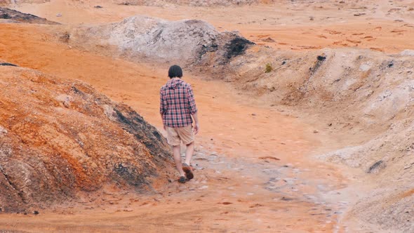 Young Man Walking on an Orange Clay Mountains