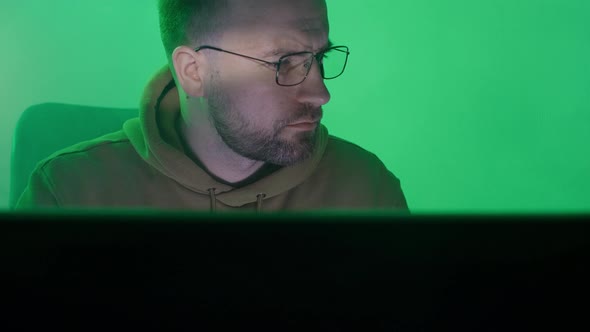 A Caucasian Man in Glasses Works on the Computer Types Checks the Information Coding Studying