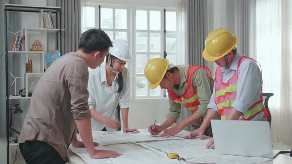 Three Asian Engineers With Helmets Drawing Building Construction For A Man At The Office