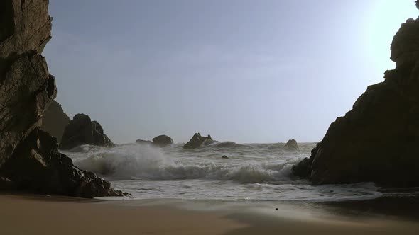 Surf on a Sand Beach Between the Rocks