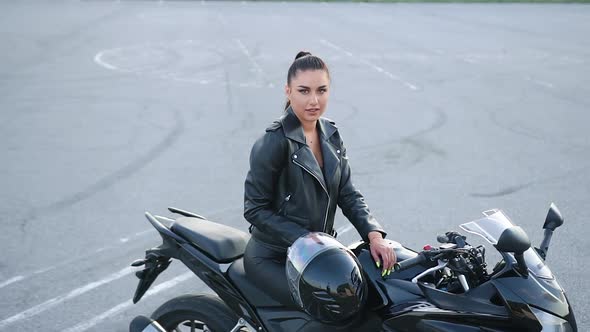 Woman in Black Clothes Sitting on Luxurious Motorcycle and Looking at Camera