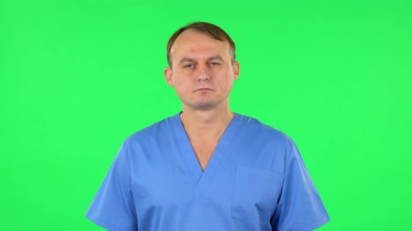 Medical Man Carefully Looks at the Camera in Frustration, Green Screen