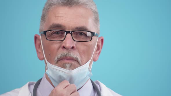 Adult Doctor with Glasses Removes Medical Mask and Looks at the Camera Closeup