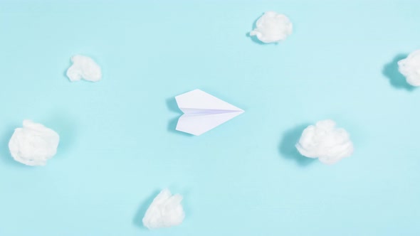 White paper airplane takes off, describing a circle and flies through the clouds, then lands.