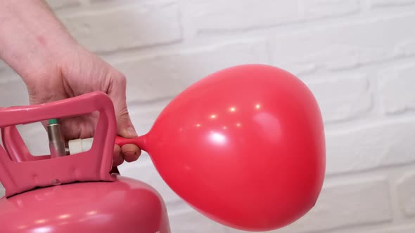 Man Hand Inflating Red Heart Shaped Balloon with Helium From Balloon