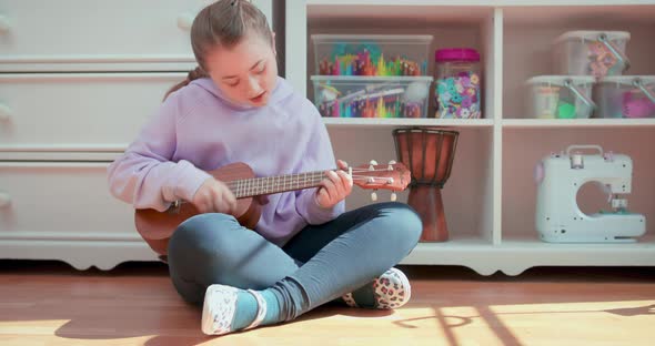 Teen Girl Sits on the Floor Pets and Kisses the Dog