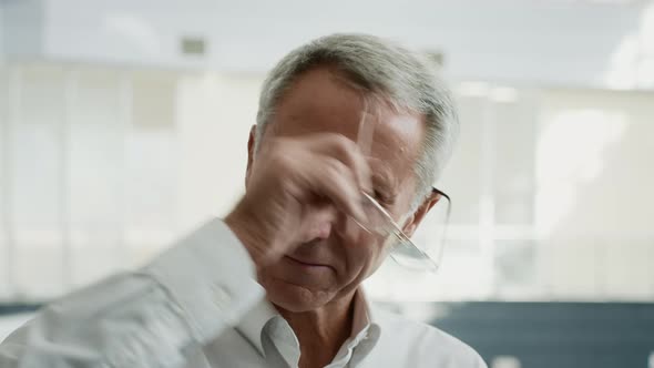 Portrait Of Contented Mature Entrepreneur Taking Off Eyeglasses In Office