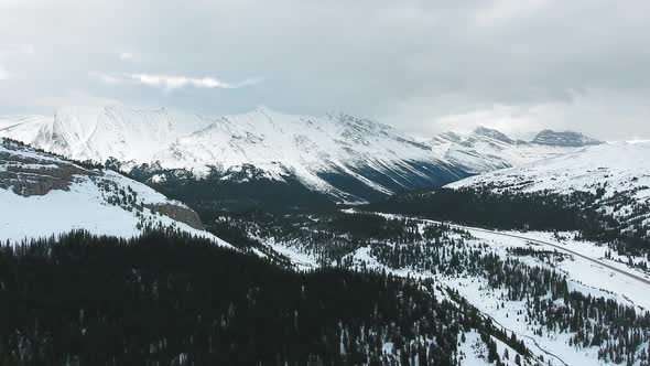 Aerial landscape of winter forest and snow-capped rocky mountains in Alberta, Canada