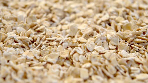 Rolled crushed oatmeal flakes close-up. Cereal raw morning porridge. Macro