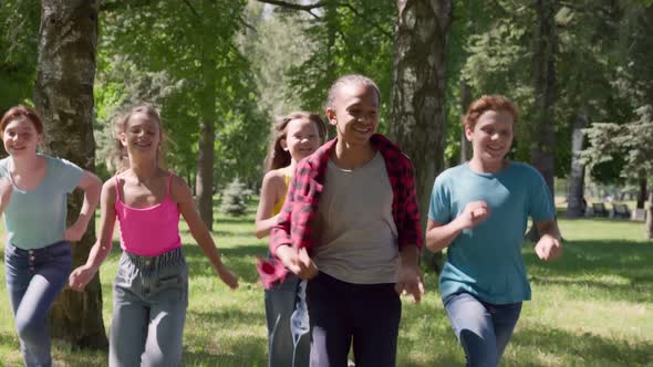 Slider Shot of Diverse Happy Kids Playing Catchup Game and Running in Summer Park