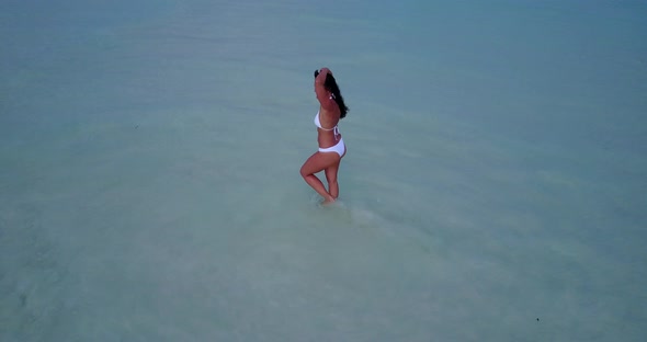 Sexy smiling girl travelling spending quality time at the beach on clean white sand and blue backgro