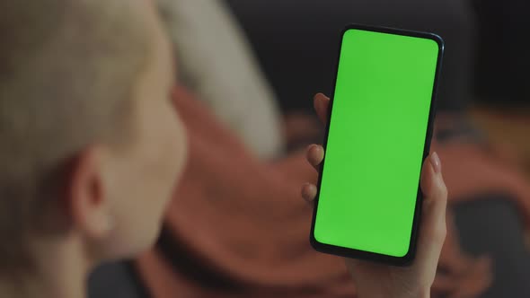 Woman Holding Smartphone with Green Screen at Home