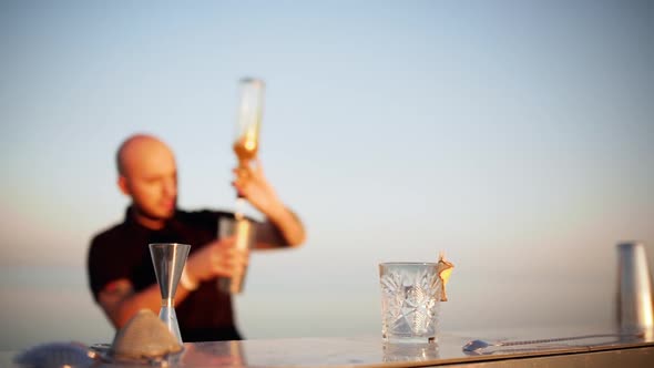 Young Handsome Bartender Preparing Cocktail in Shaker at Seaside Slow Motion