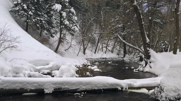 Flying over river surrounded by deep snow in winter