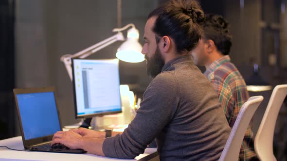 Programmers with Computers Working Late at Office