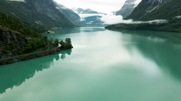 Turquoise lake waters flowing past under drone flying at Loen, western Norway.