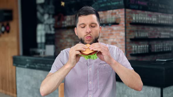 Casual Attractive Male Biting Desired Delicious Hamburger with Meat Lettuce and Vegetable