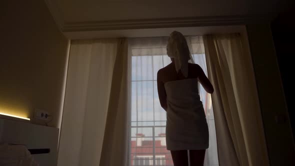 Woman in a Towel After a Bath is Standing Next to an Open Door on the Balcony