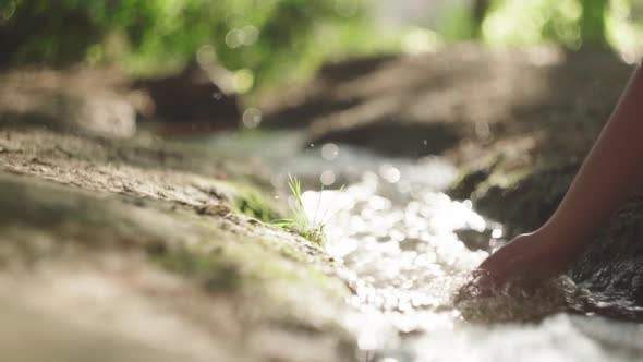 Crop woman touching flowing water in river at night