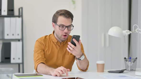 Young Man Celebrating Success on Smartphone 