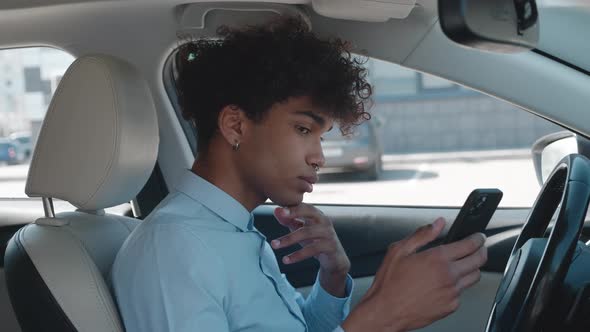 African Businessman Looks Thoughtfully at the Smartphone Screen