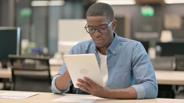 Attractive Young African American Man Using Tablet in Office