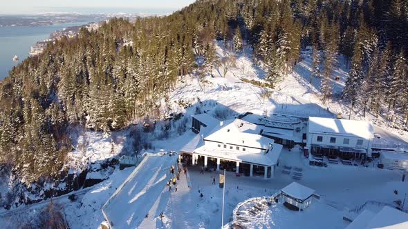 Aerial backwards view over top of the Floyen mountain covered in snow - winter scenery Bergen