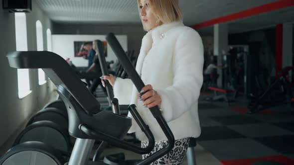 Lazy Rebel Woman Doing Exercise in the Gym in a Fur Coat and High Heels. Funny Motivation.