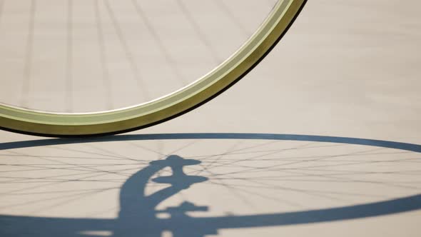 Road bike wheel spinning and casting shadow over a concrete road. Loop animation