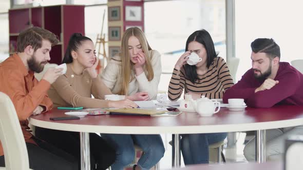 Group of Tired Adult Caucasian Students Sitting at the Table and Talking. Young College Students