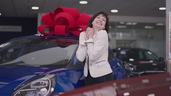 Excited Joyful Beautiful Caucasian Woman Rejoicing Car Winning Standing in Dealership at Blue