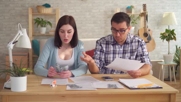 Young Couple Concerned and Tense Doing the Calculations Documents with Calculator