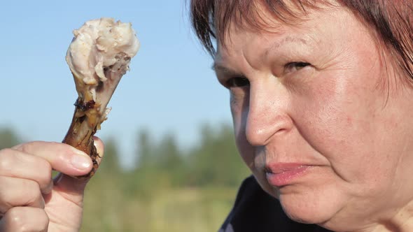 The Closer Look of the Lady Eating the Drumstick of the Chicken