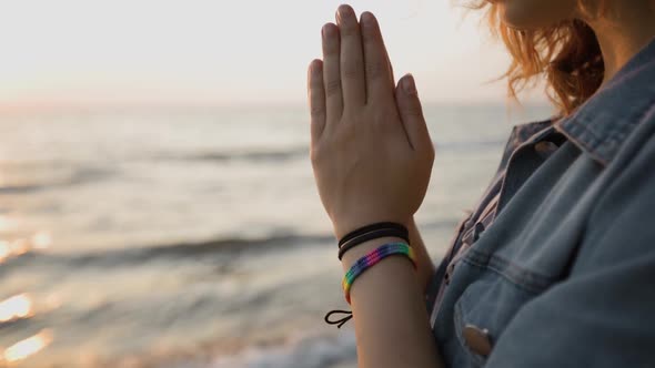 LGBT Pride: Woman Wears Rainbow Bracelet and Prays at Sea