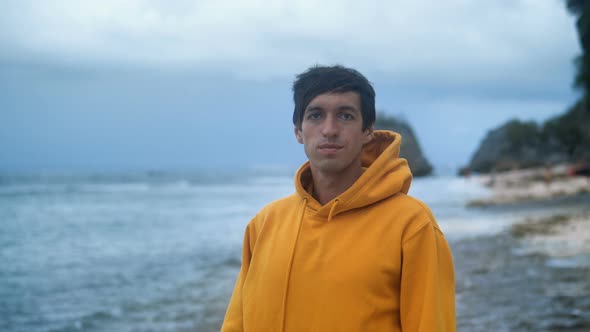 Portrait of a Young Male Traveler in the Evening on a Wild Tropical Beach Before Thunderstorm