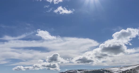 Time Lapse of Cloudscape Behind of the Mountains Top. Snow, Rocks, Cliffs and Deep Blue Sky. High