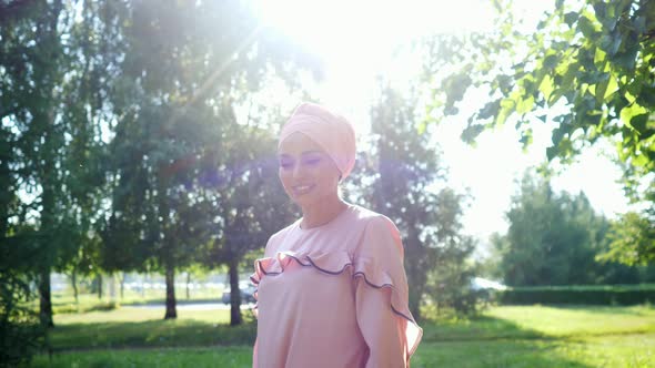 Elegant Lady in Long Purple Dress and Hijab Walks Along Park