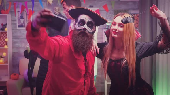Spooky Pirate and Bloody Witch Characters Taking a Selfie at Halloween Party